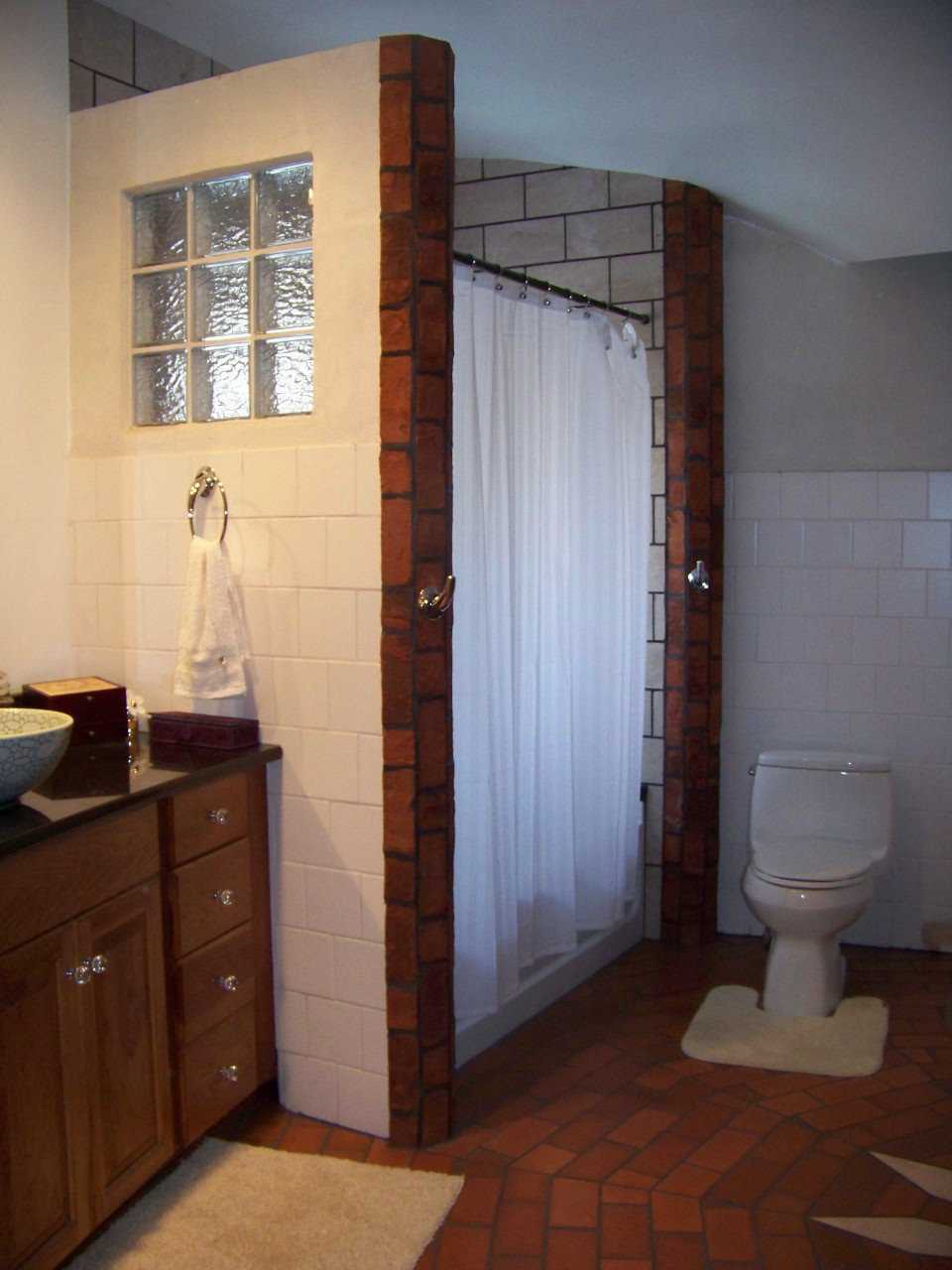 Tile shower — This bathroom sports tile walls and a brick floor with an eye-catching design.