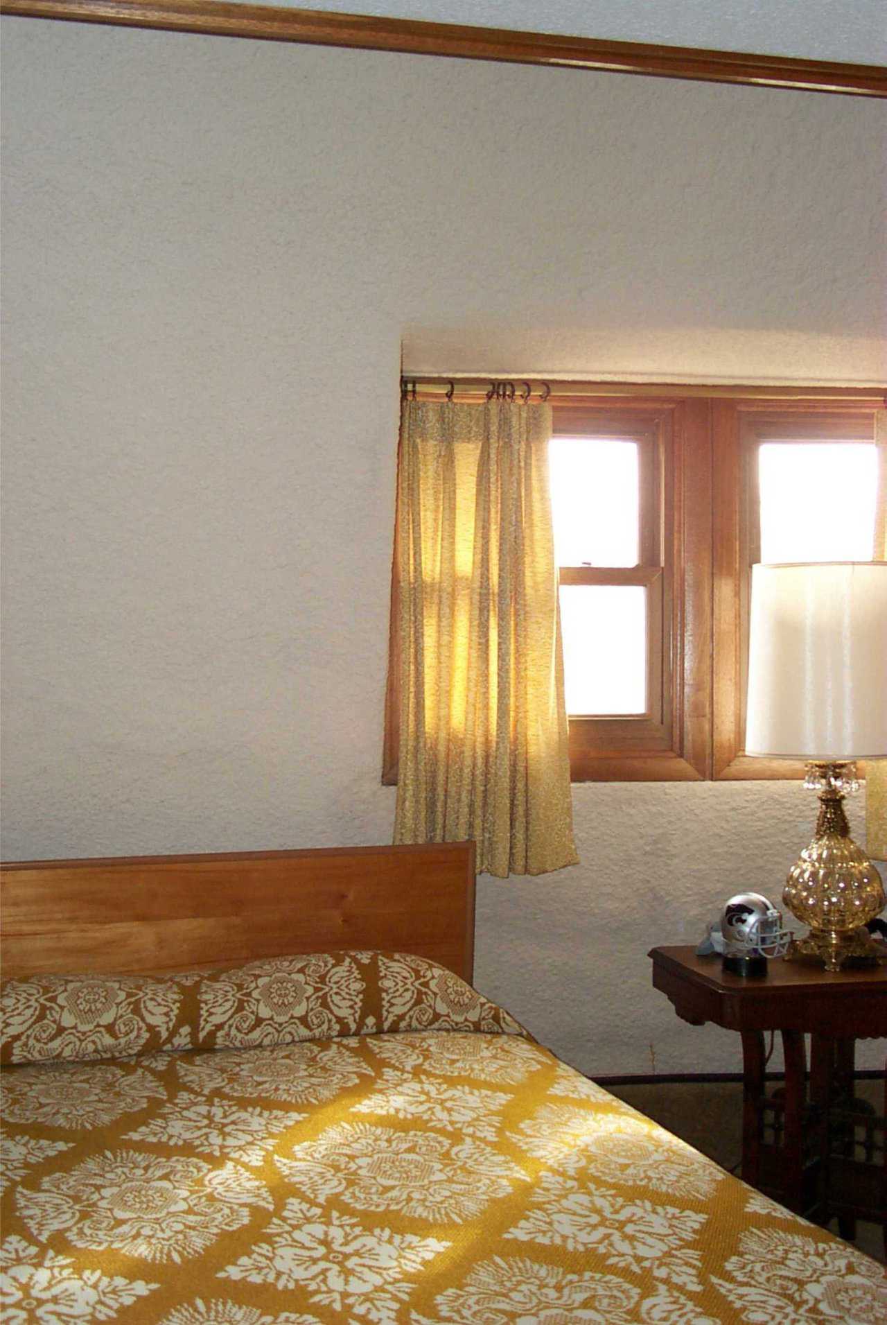 Bedroom — Warm winter sunlight enters the spacious bedroom through wood framed windows.