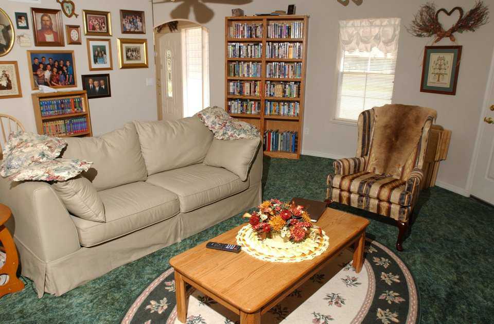 Coziness — Second living area is adjacent to the home’s main entryway. Large bookshelves, entertainment center and a deep green carpet add to the room’s warmth and comfort.