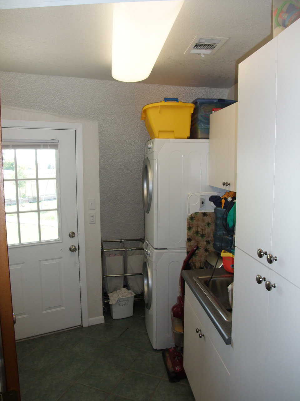 Laundry area — in addition to the washer and dryer, it includes a sink and storage cabinets.