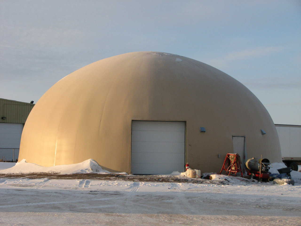 Figure 2.9 — Heated Monolithic Dome shop in Sasketoon, Saskatchewan, Canada.  The outside temperature at this time was 13 degrees Fahrenheit below zero (-25C). This is a standard color photograph taken by a standard camera.  Note the metal buildings in the background.