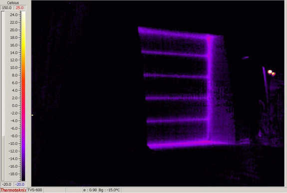 Figure 2.10 — This picture shows the same Monolithic Dome through the thermographic camera at the same 13 degrees F below zero.  Note the Monolithic Dome is black.  This is a heated shop.  There is no heat loss through the dome shell.  The door (insulated) is leaking heat, especially at the cracks between the sections and along the edges.