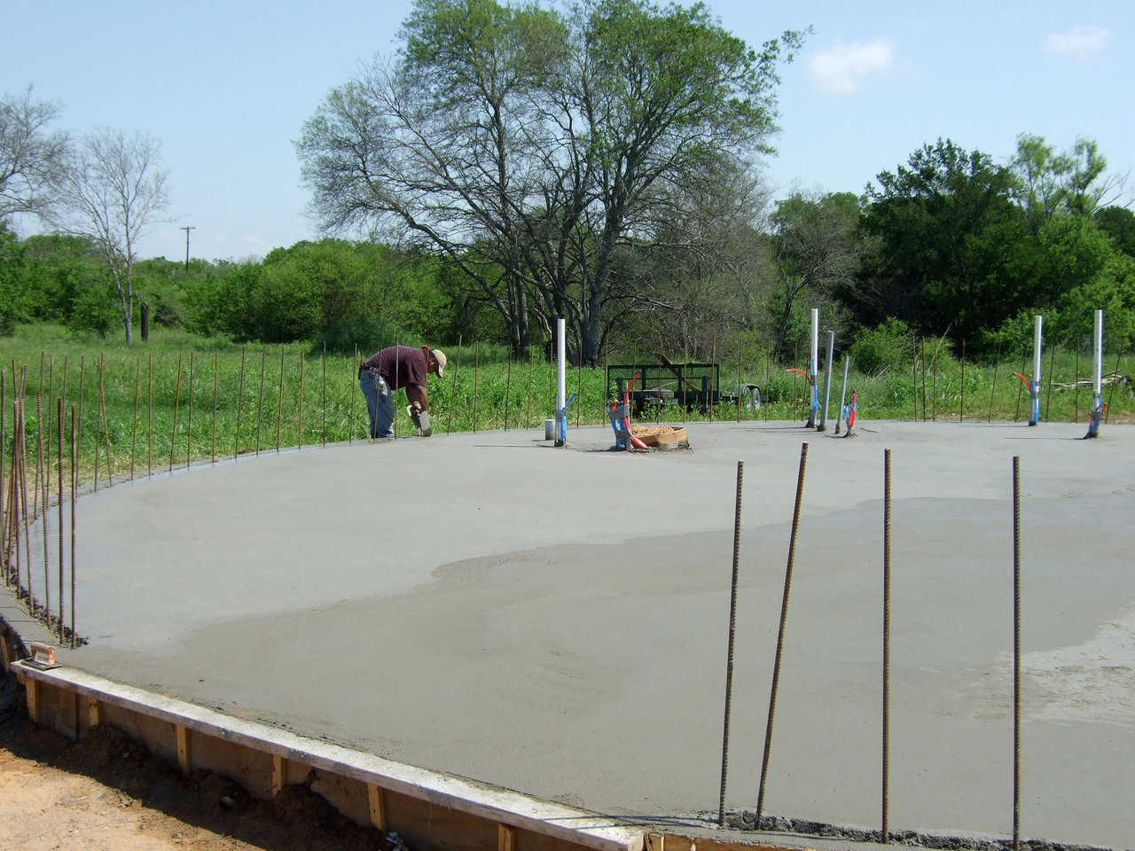 Concrete Floor — Our crew had just finished pouring a concrete floor for a new Monolithic Dome home.  A worker walks around the floor, cutting out the keyway.  The keyway is the 2" wide cutout that goes around the rebar uprights.