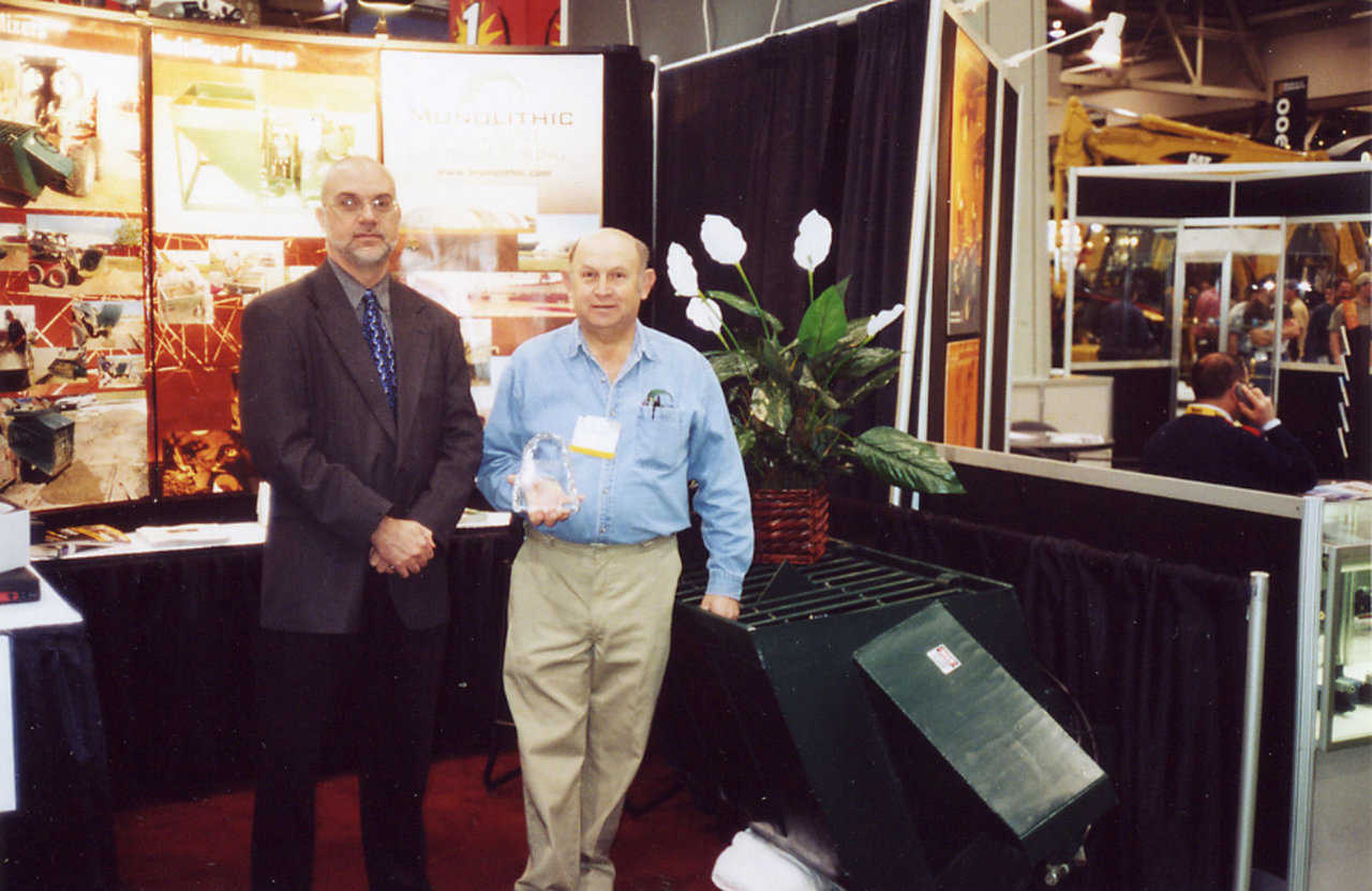 Award — In 2002, Rod Sutton (left), Editor In Chief of Construction Equipment Magazine, presented Blaine Green, Monolithic Equipment Manufacturing Division Manager, an award for the design of the Monolithic Portable Concrete Mixer.