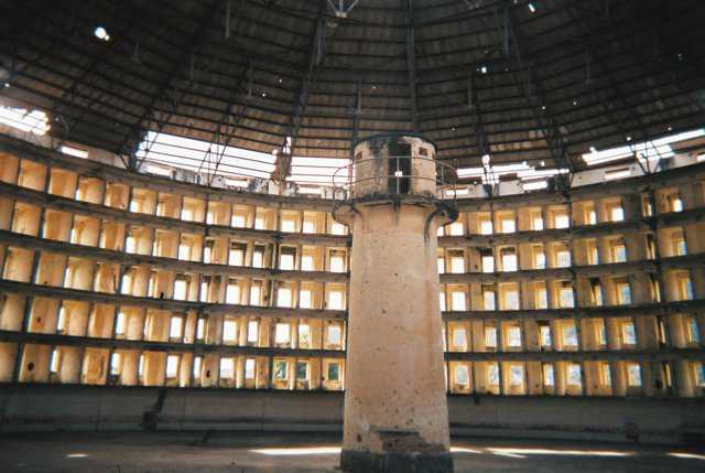 The Interior of the Presidio Modelo — The architecture incorporates a tower central to a circular building that is divided into cells, each cell extending the entire thickness of the building to allow inner and outer windows. The occupants of the cells are thus backlit, isolated from one another by walls, and subject to scrutiny both collectively and individually by an observer in the tower who remains unseen.