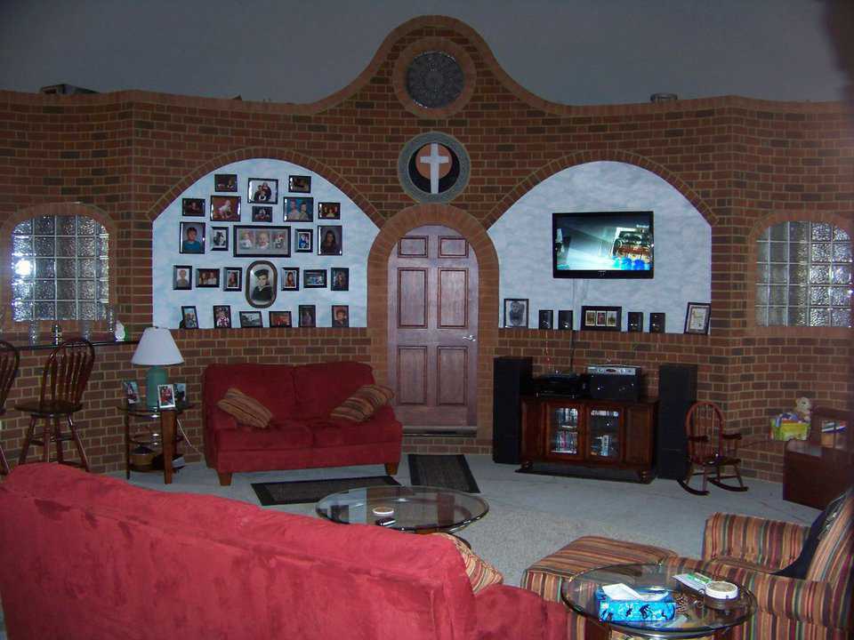 A den of fond memories — Accented by their curved brick arches, the den walls display a collection of family photos.