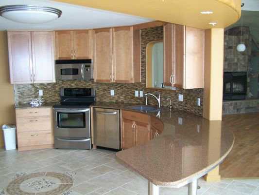 Kitchen — It includes a beautiful tile floor, wood cabinets, stainless steel appliances and a curved, marble-like counter.