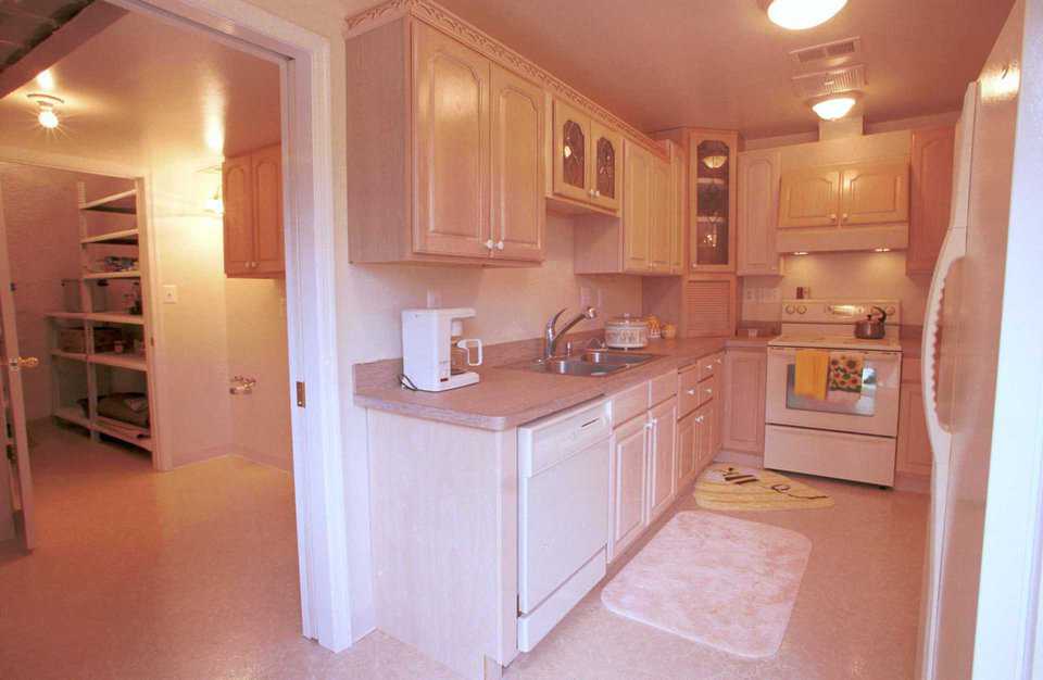 Kitchen — Combination oak and maple cabinets with a white washed finish outline the efficiently designed kitchen.  Carved wood trim above cabinets adds detail and visual interest.  A large pantry/storage area and the oversized laundry room are adjacent to the kitchen.