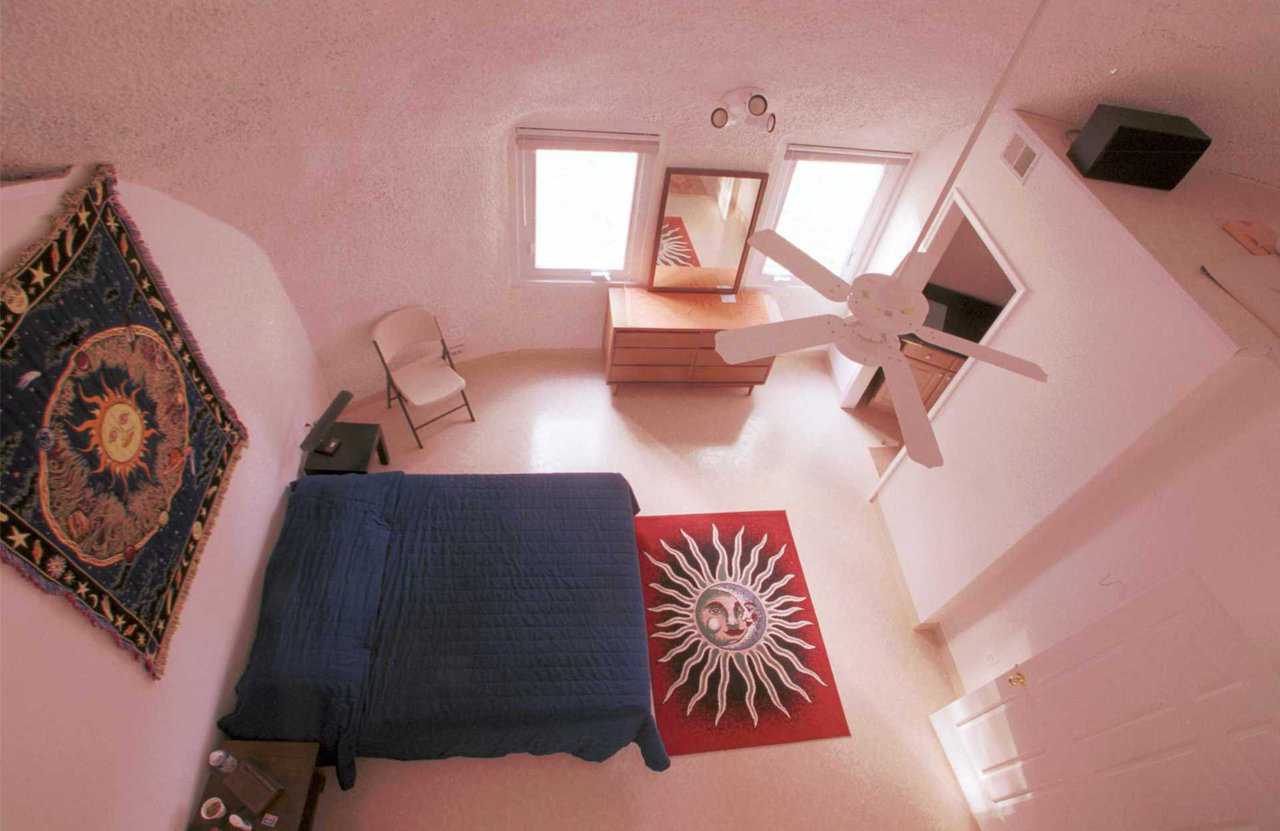 Loft-view of Master Bedroom — View of the master bedroom from the loft displays the open ceiling.  The vinyl floor provides a beautiful, easy-to-maintain interior floor finish.  The loft provides additional storage space or additional sleeping quarters for guests.  The framing in the ceiling peak is for a future motorized remote-controlled skylight.