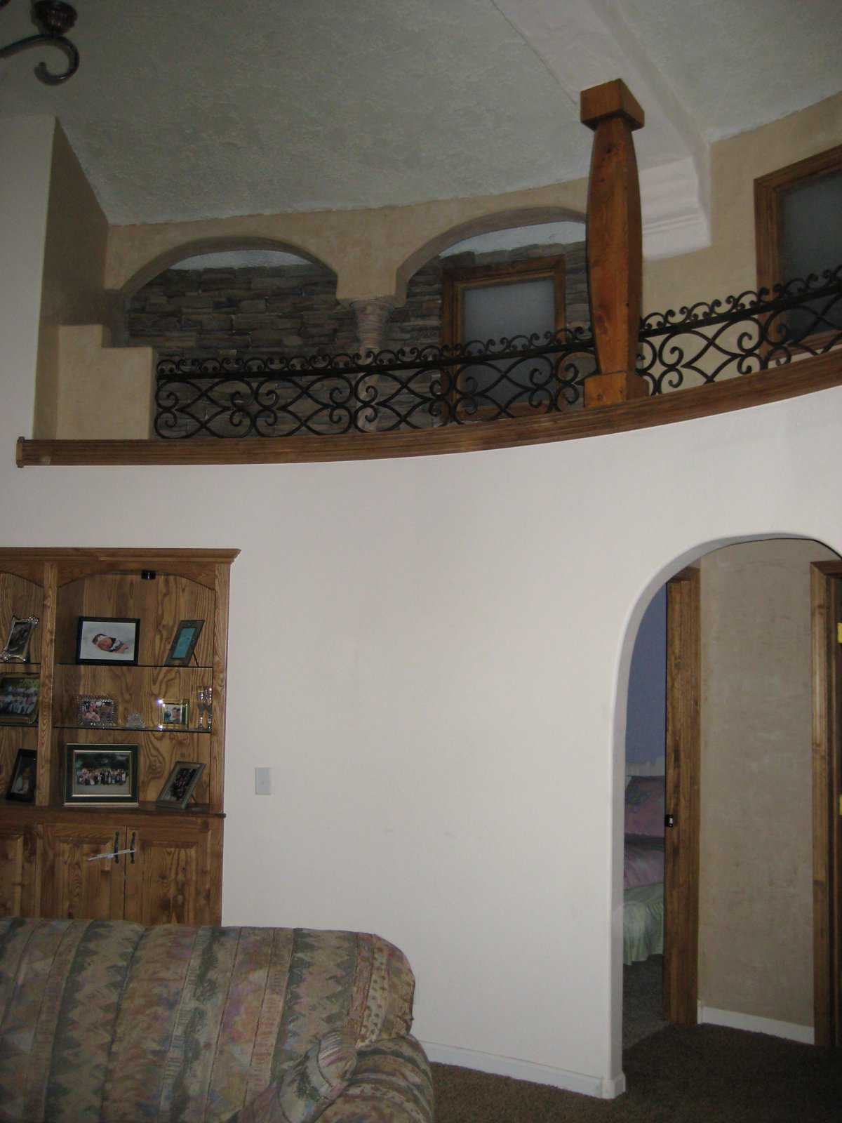 An illusion — A shallow, wrought iron banister, windows and beams create the illusion of a second level overlooking the family room.