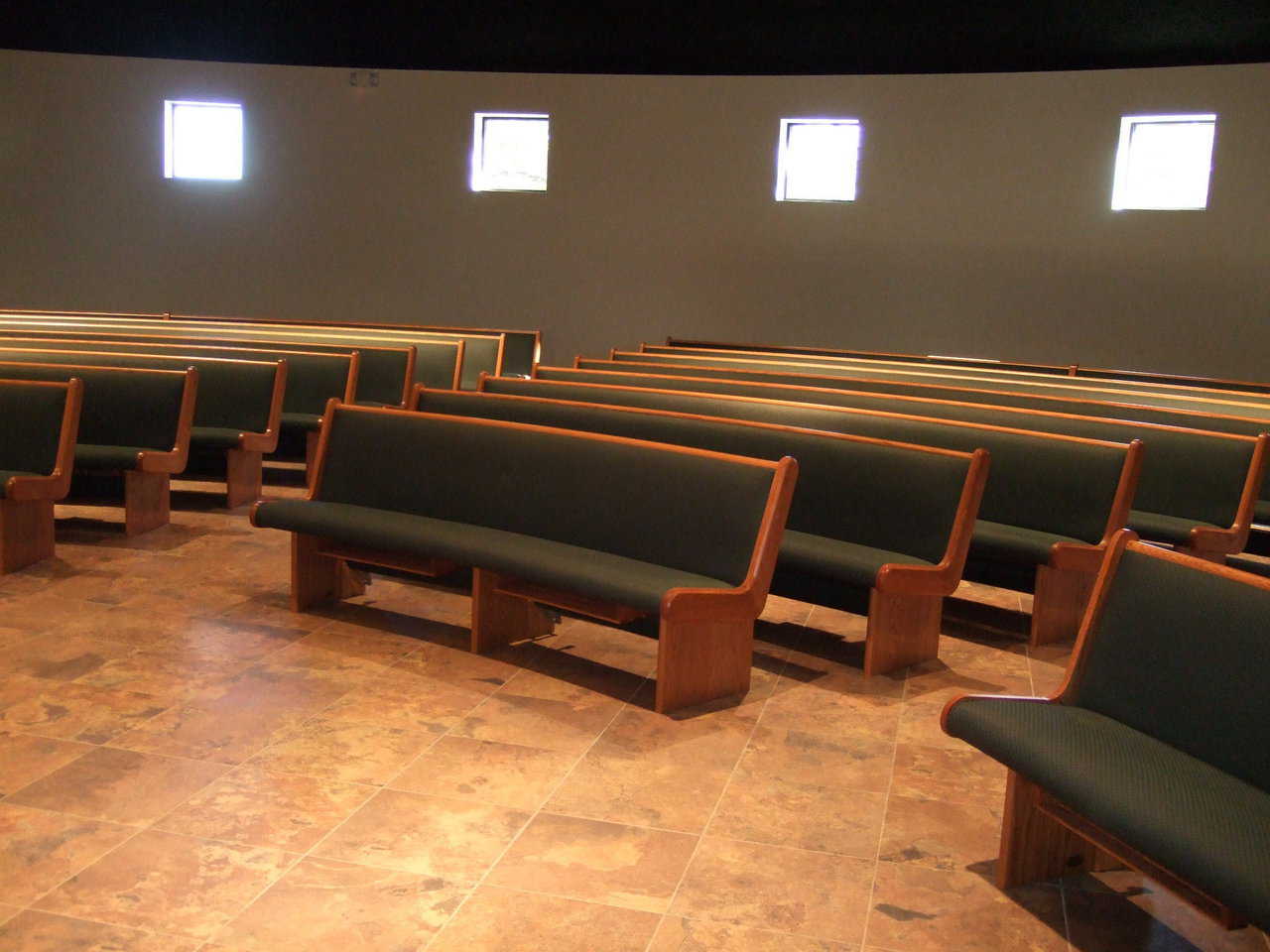 Comfortable seating — Curved wooden pews, upholstered with a cushiony soft green fabric, help create an intimate atmosphere while providing ample seating.