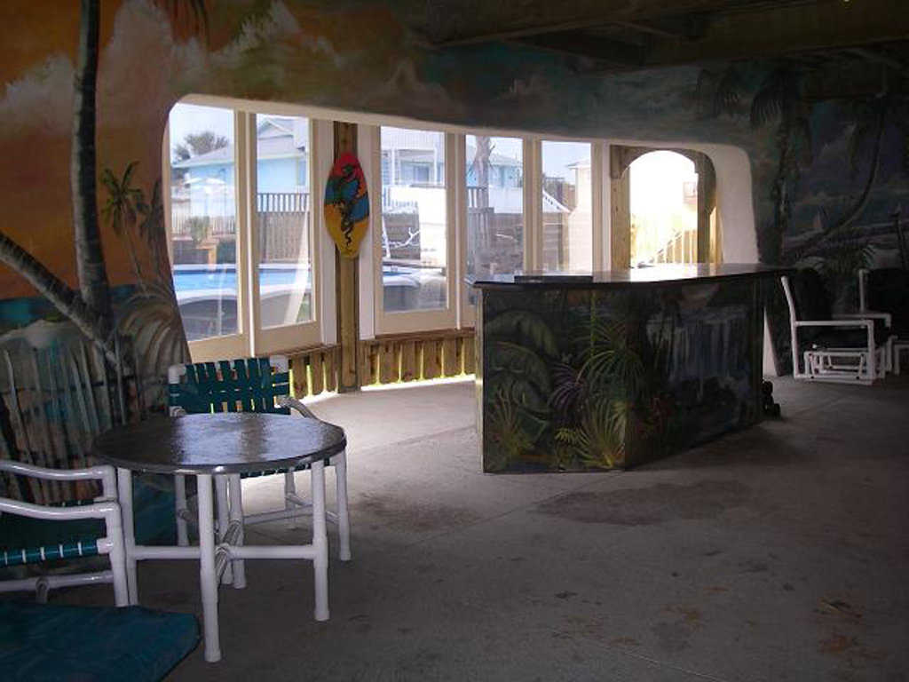 Patio — Walls enhanced with swaying palms and blue skies make the beach seem like a part of this enclosed patio.