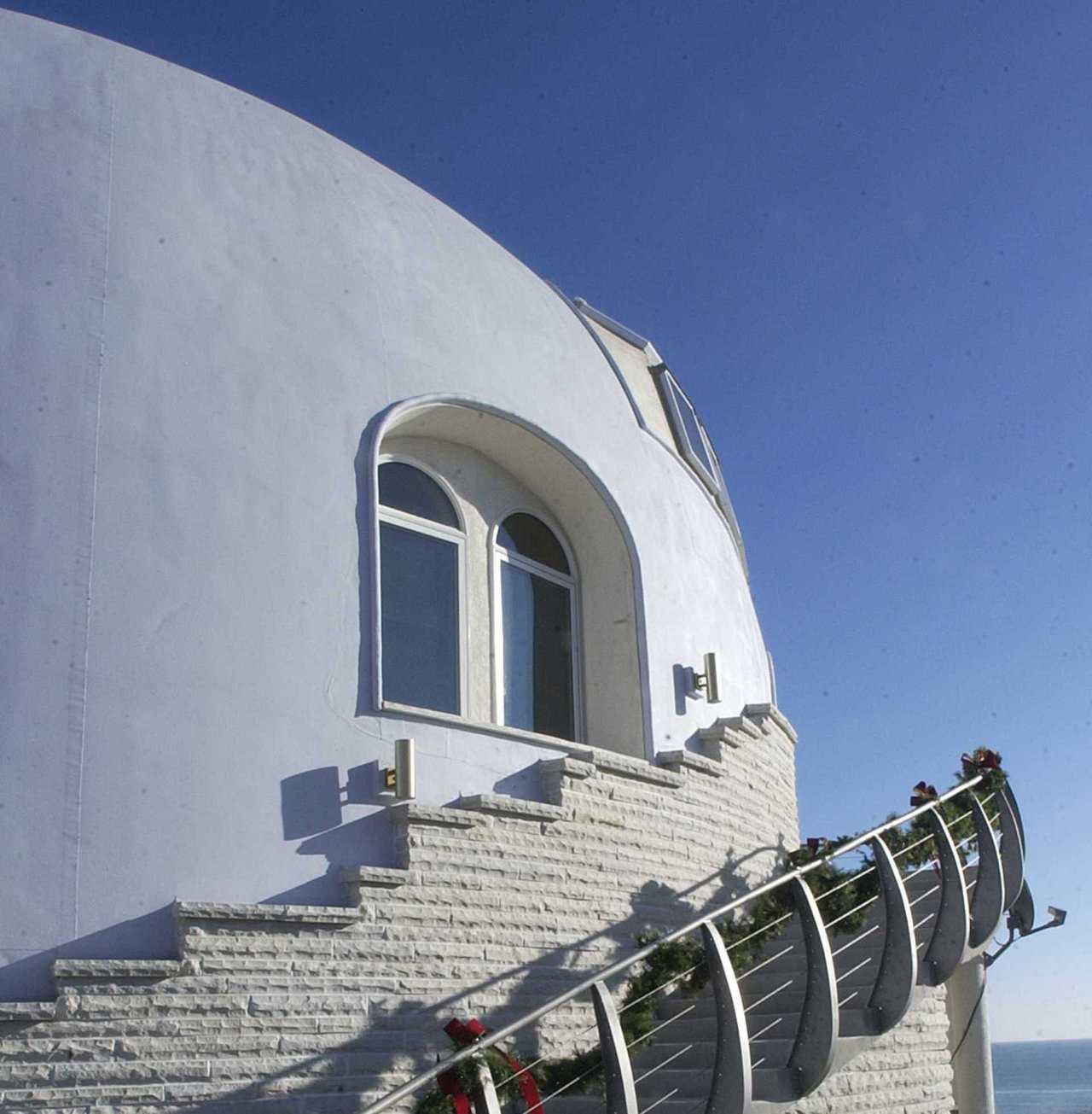 Outside Stairway — A curved, concrete stairway leads from the lowest level and ascends to the main living area. Limestone from a nearby quarry skirts the base of the dome.