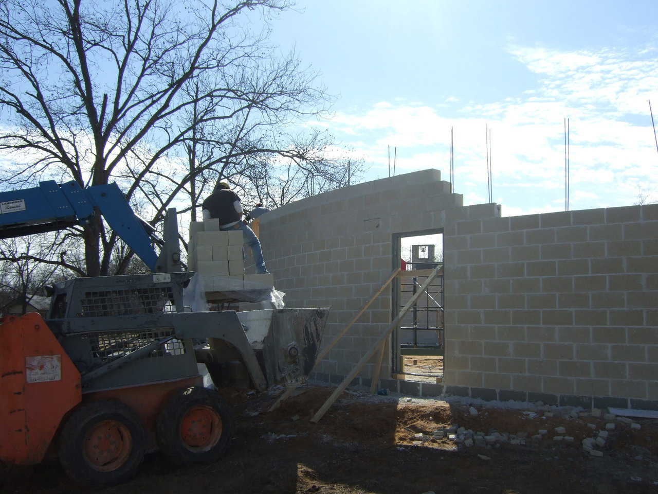 Image form the outside.  The forklift is delivering the blocks, and the skid steer is delivering the mud.  The bobcats ability to go through even the roughest territory makes moving the mortar very simple.  Imagine using  wheel barrow through that mud, or even moving the mud in a standard skid steer bucket without loosing half the batch.