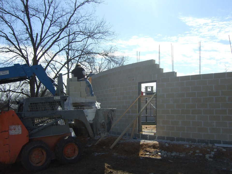 Image form the outside. The forklift is delivering the blocks, and the skid steer is delivering the mud. The bobcats ability to go through even the roughest territory makes moving the mortar very simple. Imagine using wheel barrow through that mud, or even moving the mud in a standard skid steer bucket without loosing half the batch.