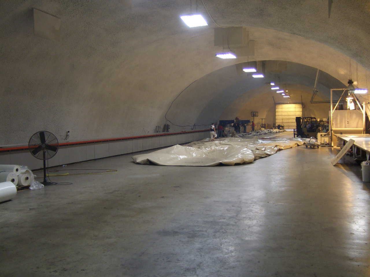 Bruco is 60’ wide, 240’ long, with a floor area of 14,000 sq ft. Generally, a crew of six to eight work inside. The table on the right holds two, state-of-the-art, radio frequency, fabric welders and is used for cutting and assembling patterns. The ceiling paint is an updated whitewash.