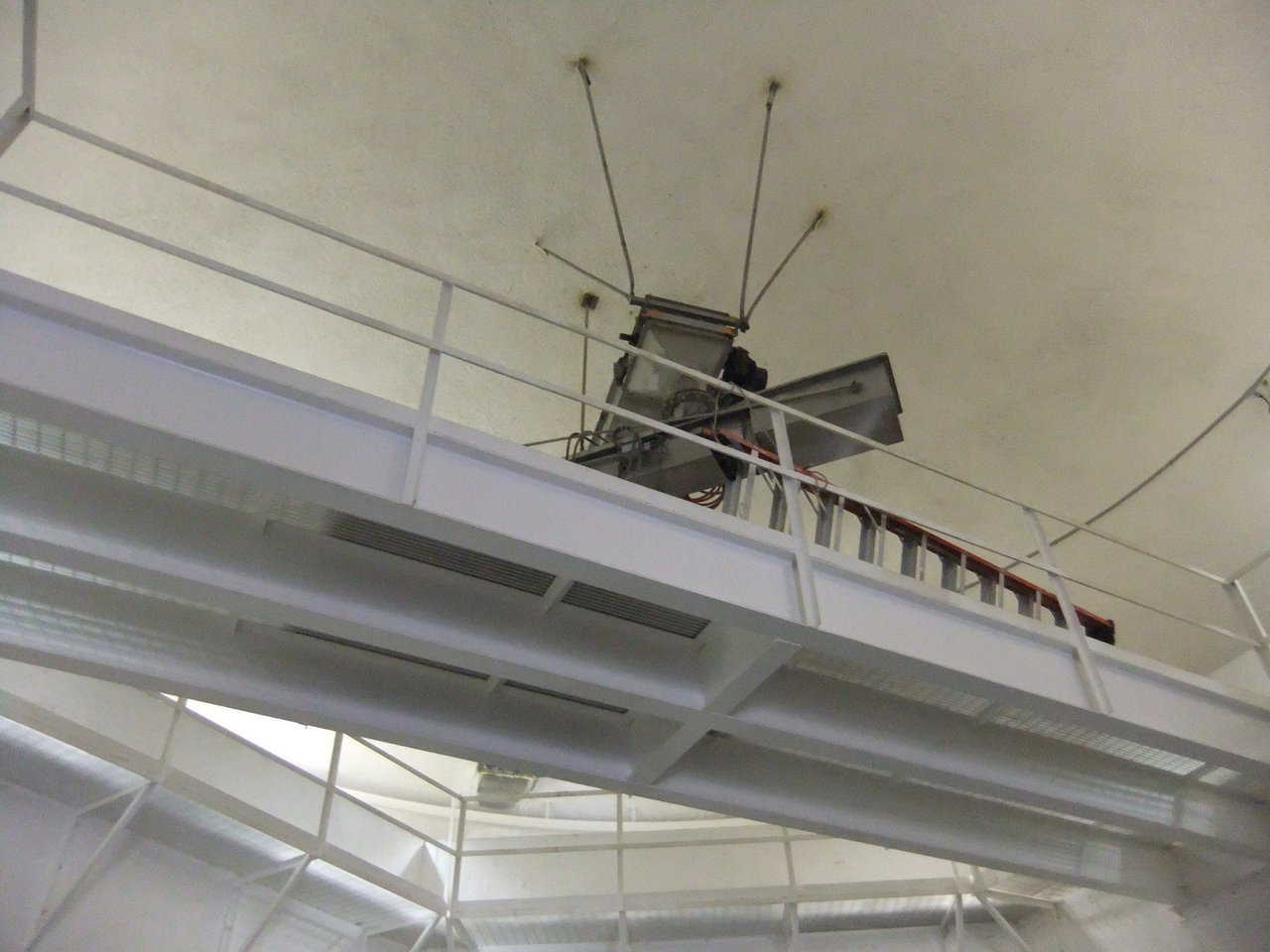 Easy access — Shown immediately above the camera is the catwalk that allows those operators to walk back and forth from one side of the bin walls to the other. From that catwalk they can service the inbound conveyor as well as the rotating conveyor. Note: Those are all supported from the five legs hanging down from the ceiling.