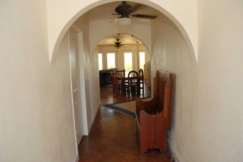 The hallway opens into a dining area with multiple windows.