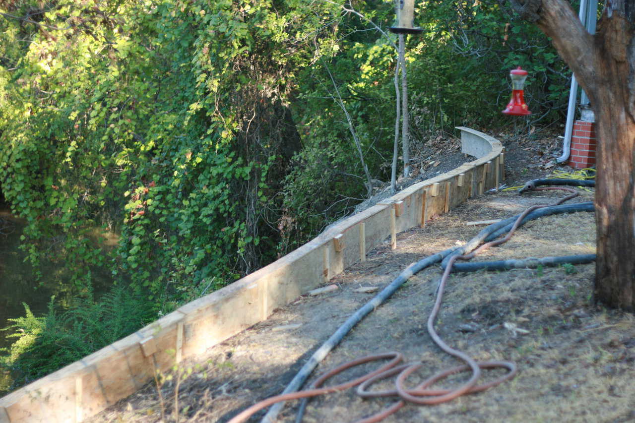 We began by embedding serious post holes at the bottom where the bank levels out. We poured concrete into these post holes, down through the water, which was simple to do. We used a substantial amount of concrete to protect the rebar at this location.