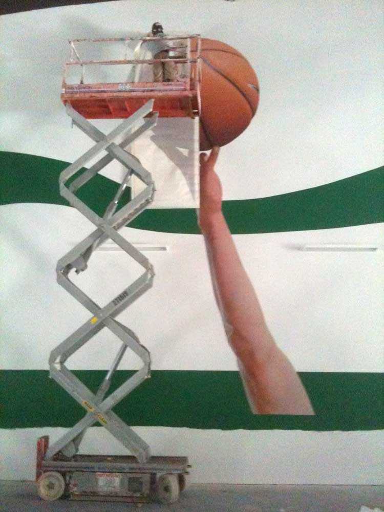The challenge of Woodsboro’s enormous wall was getting the cutout graphics affixed without building a scaffold, since the wall was higher than any conventional extension ladder. Mural installers of Corporate Installations finally settled on using an electric scissor lift to reach the highest levels.