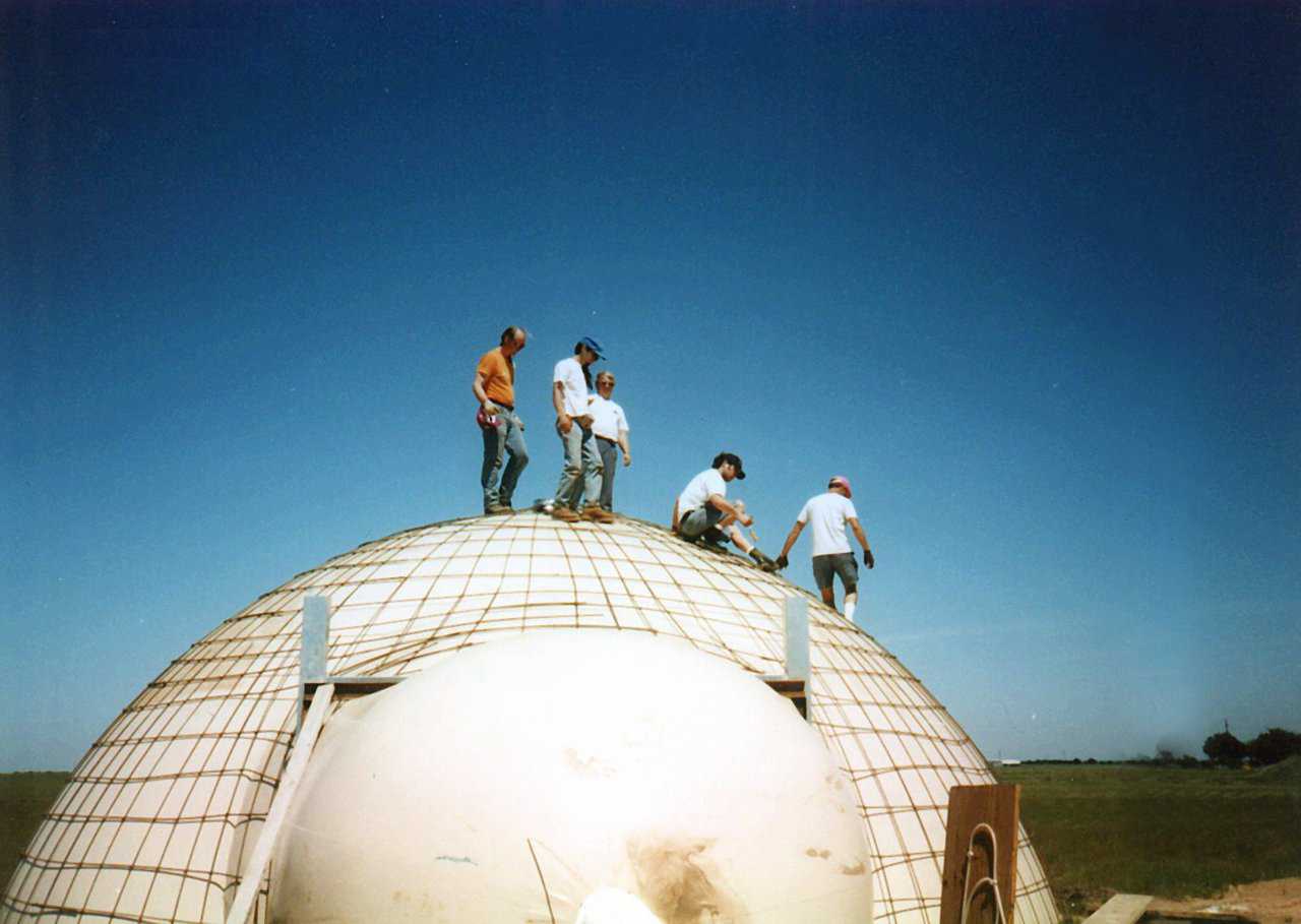 When building an Ecoshell I, we use about six to eight inches of water column pressure. As can be seen, that’s a huge amount of uplift. These men are totally supported by the Airform, atop the reinforcing. The door augmentation will be added before it’s concreted.