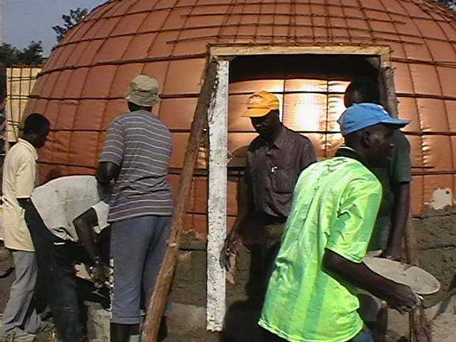 Workers and volunteers apply concrete on an EcoShell.
