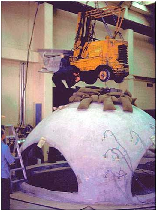Strength testing the Monolithic Dome at BYU Laboratories. The sand bags represent the amount of weight previously thought to be the maximum load this dome could take. The addition of the forklift did nothing. They were ultimately unable to break the shell by overloading it and had to take it apart with jackhammers.