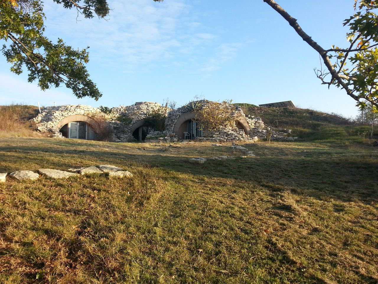 This bermed Monolithic Dome home belonging to Al Schwartz is covered with a spectacular combination of natural stone from the area and local vegetation.