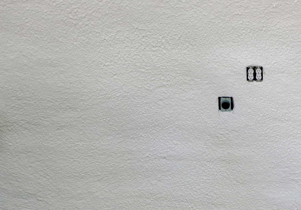 No penetration or damage is evident on the concrete interior after five close-range shots (aimed at area left of outlets).