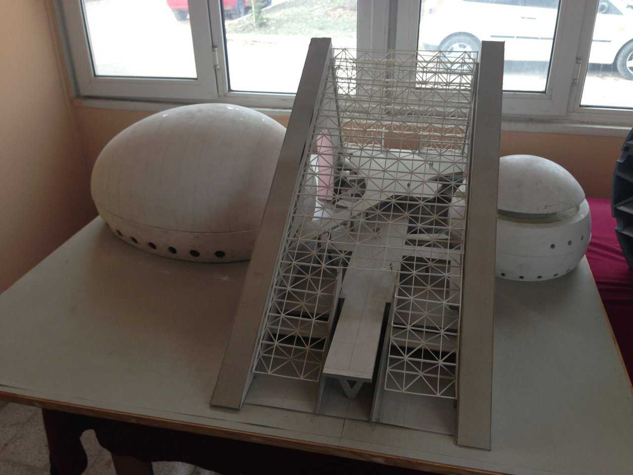 A model of the finished exterior of the colossal ellipsoid dome and its impressive spherical counterpart, juxtaposed with the vaulted triangular foyer, under construction in downtown Ankara, Turkey on Ataturk Boulevard.