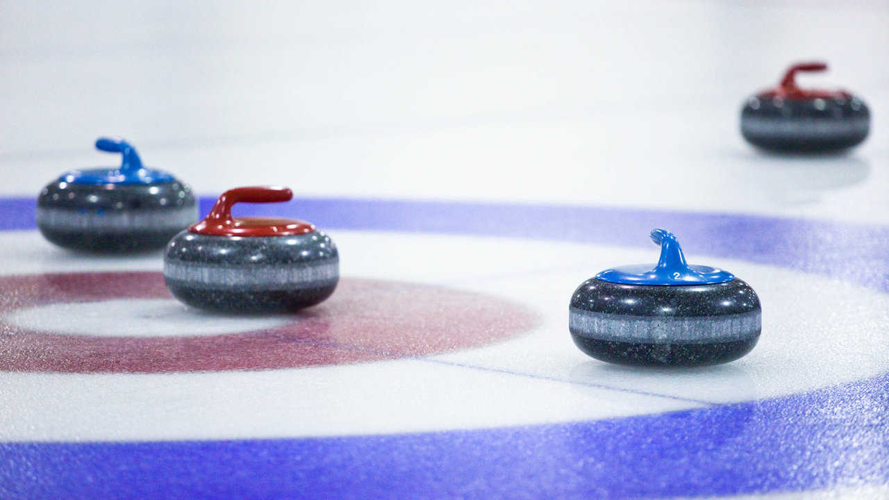 Curling stones on the pebbled ice surface.