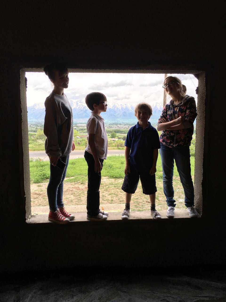 Amy, Sam, Tom and Aubrey sizing up the large window in the sun room with its view of the valley and mountains in the west.