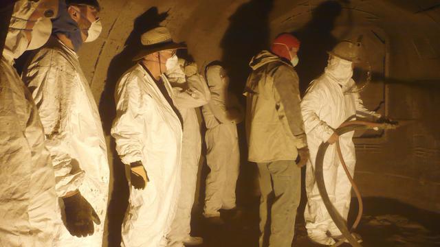 Students take turns applying shotcrete to a Monolithic Dome they built during the workshop.